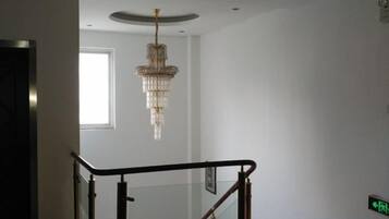 A staircase with a glass railing and a chandelier.