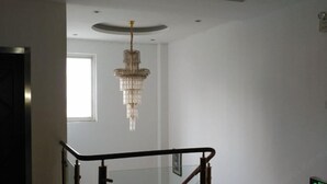 Una escalera con barandilla de cristal y un candelabro.