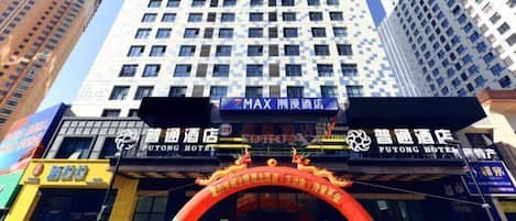 A hotel entrance with a large archway and multiple signs, including one for Putong Hotel.