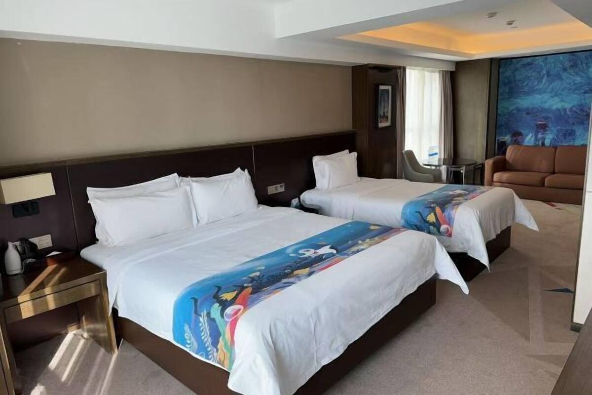 A hotel room with two beds, a nightstand, a chair, and a painting on the wall.