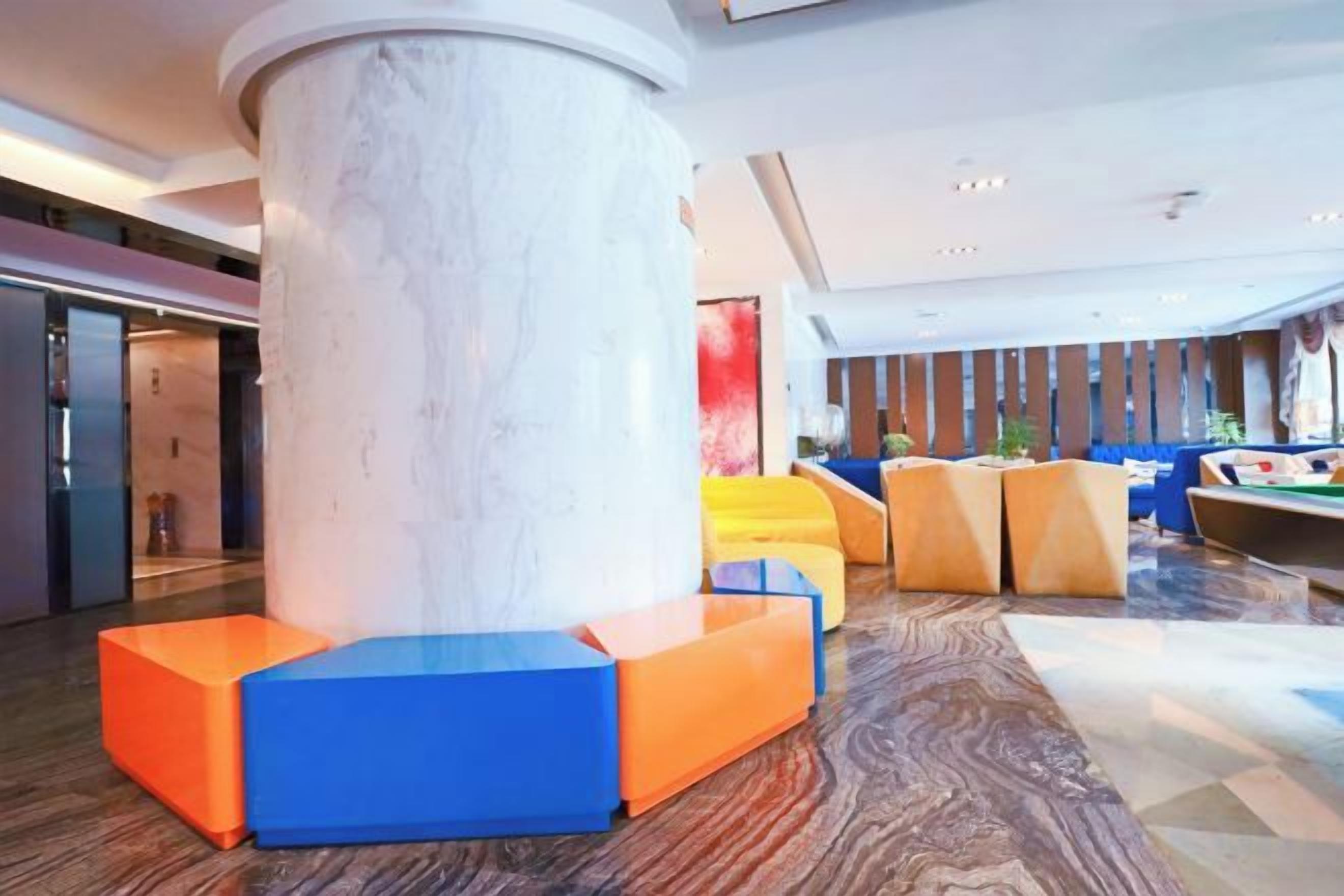 A modern lobby with a marble column, seating areas, and a pool table.