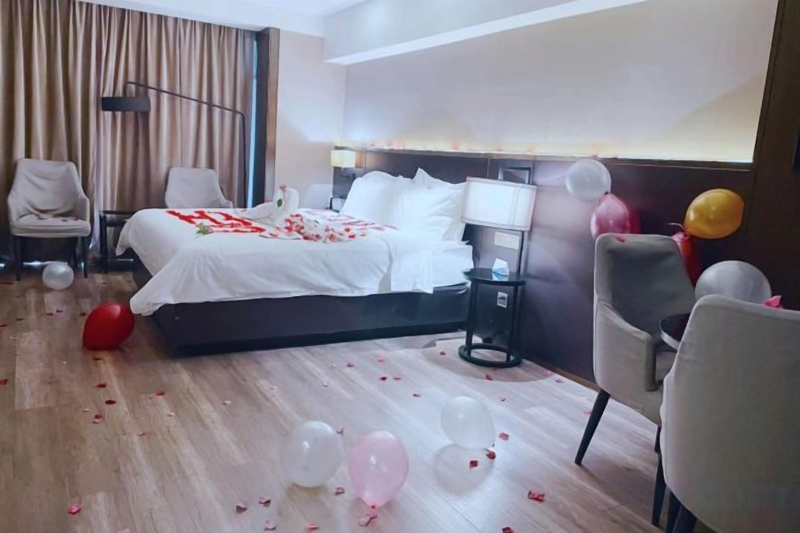 A hotel room with a bed, bedside tables, a lamp, and a chair.