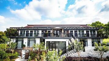 Un edificio moderno su due piani con un balcone, una scala e un’area giardino.