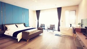 A modern bedroom with a large bed, a sofa, a desk, and a TV. - Donglai Manor Hotel (Shanghai)