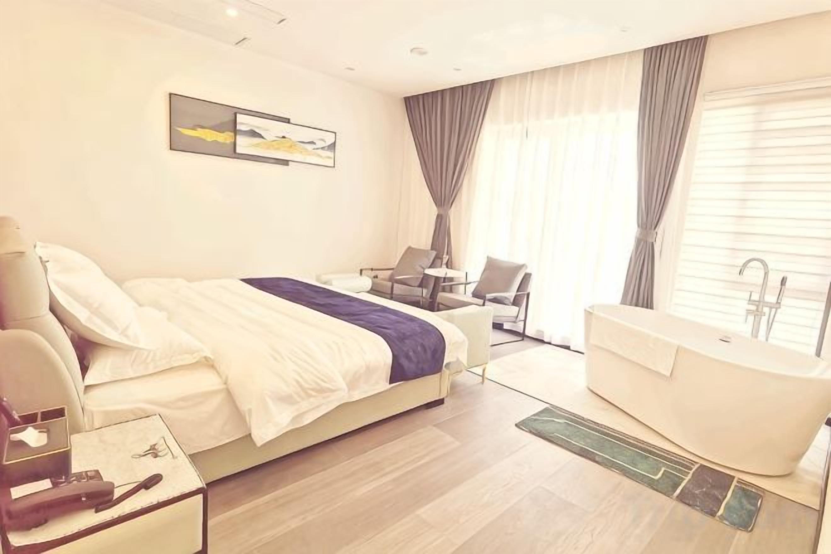 Une chambre d’hôtel avec un lit, un bureau, une chaise, une baignoire et une fenêtre avec des rideaux.