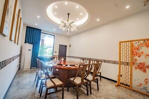 Zona pranzo con tavolo rotondo, sedie, un lampadario e un pannello decorativo.