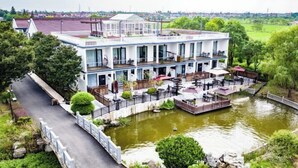 A multi-story hotel with a river view, outdoor seating, and a bridge. - Donglai Manor Hotel (Shanghai)