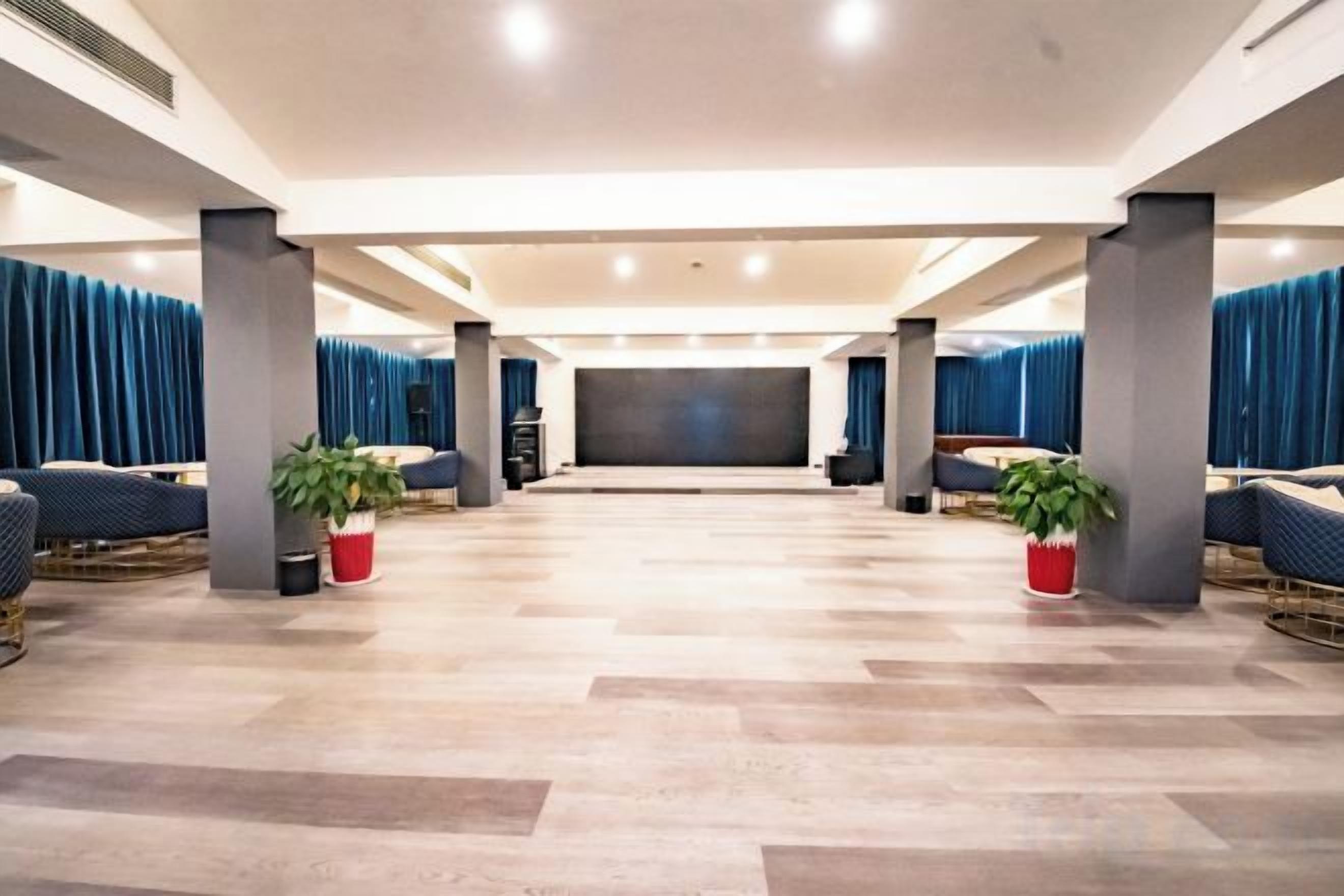 A spacious room with a flat-screen TV, seating area, and potted plants.
