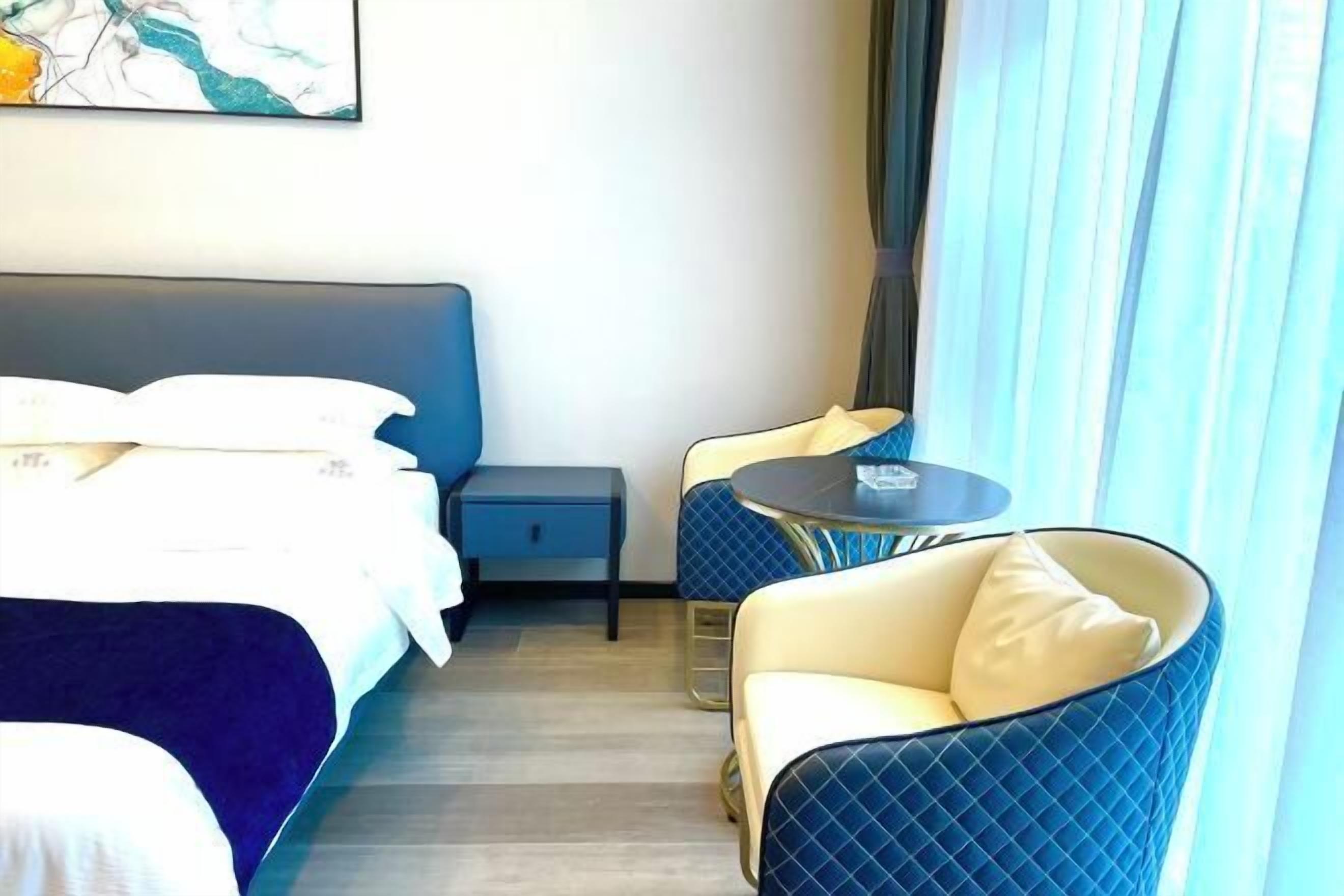 Quarto de hotel com uma cama, uma pequena mesa de cabeceira, uma cadeira e uma mesa redonda.