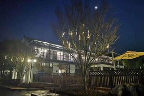 A building with a balcony, a tree in the foreground, and a fence. - Donglai Manor Hotel (Shanghai)