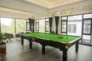 A pool table in a room with large windows and a hanging light fixture. - Donglai Manor Hotel (Shanghai)