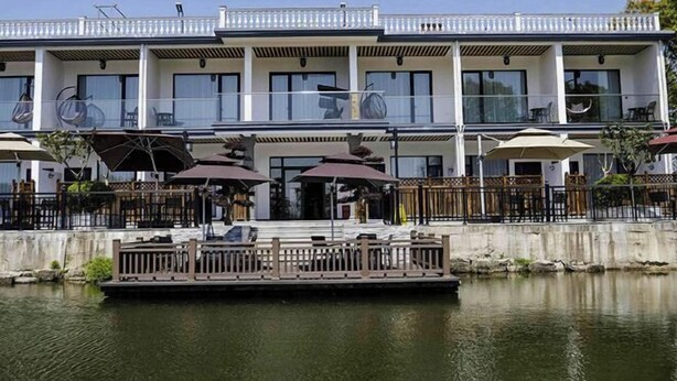 A waterfront hotel with multiple balconies, outdoor seating, and a dock. - Donglai Manor Hotel (Shanghai)