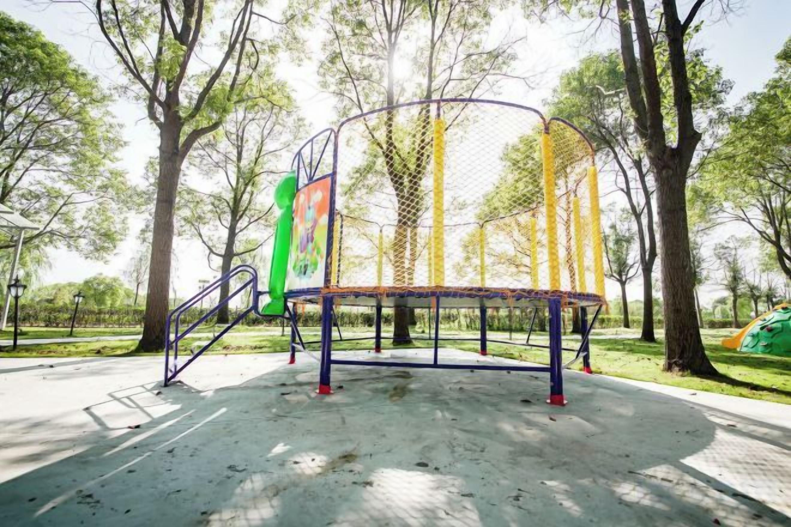 A playground with a swing set and a climbing structure, surrounded by trees.