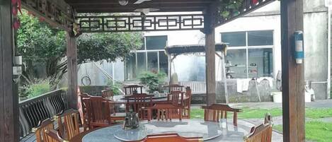 An outdoor patio with a round table and chairs, a ceiling fan, and a view of a residential area.