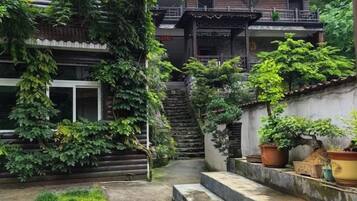 A traditional Japanese-style courtyard with a wooden staircase, potted plants, and a stone pathway.