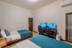 A bedroom with two beds, a desk with a computer, and an air conditioning unit. - Qingqing Inn (Dali City)