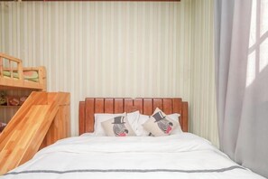 A neatly made bed with a wooden headboard, white bedding, and two decorative pillows with a skeleton design. - Qingqing Inn (Dali City)