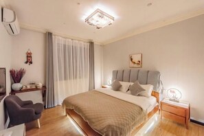 A modern bedroom with a large bed, bedside tables, a chair, and a ceiling light fixture. - Qingqing Inn (Dali City)
