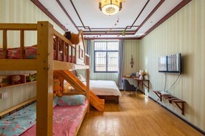 A room with bunk beds, a desk, a chair, a television, and a window with curtains. - Qingqing Inn (Dali City)