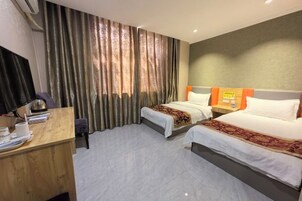 Una habitación de hotel con dos camas, un escritorio, una silla, un televisor y cortinas.