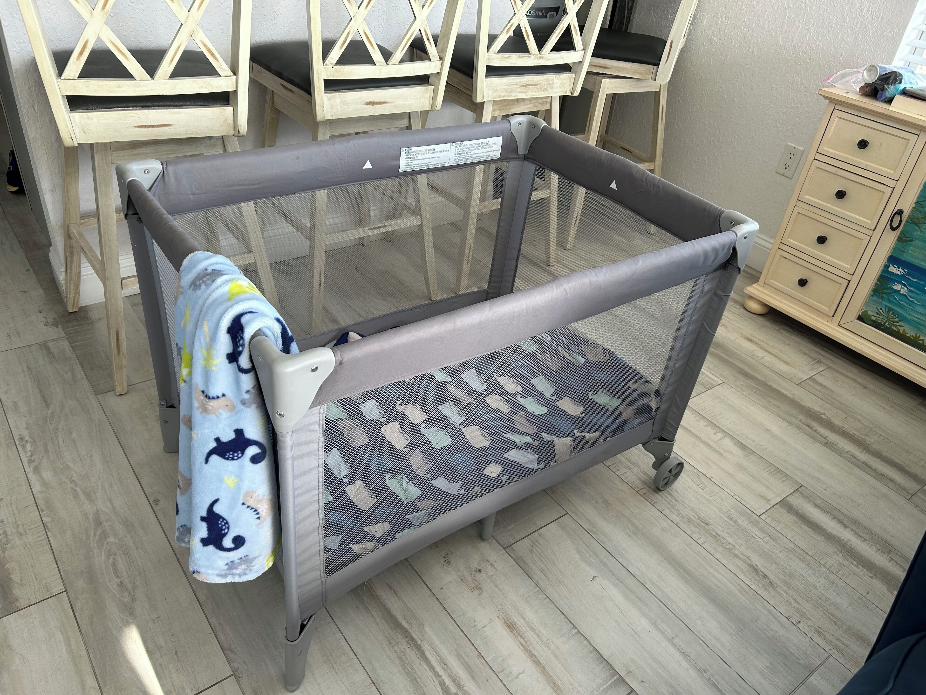 Un parc pour bébé doté d’un fond en tissu à mailles et d’une structure grise.