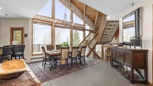 A spacious kitchen with a dining area, large windows, and a wooden staircase. - Abode at Highpoint, private hot tub, pool table, mountain retreat (Park City)