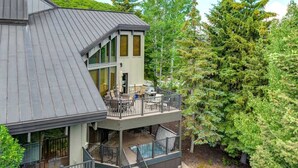 A two-story house with a balcony, a pool, and a large tree in the background. - Abode at Highpoint, private hot tub, pool table, mountain retreat (Park City)
