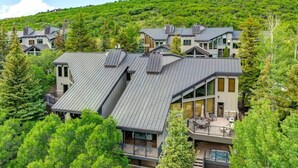 A modern multi-story building surrounded by dense green forest. - Abode at Highpoint, private hot tub, pool table, mountain retreat (Park City)