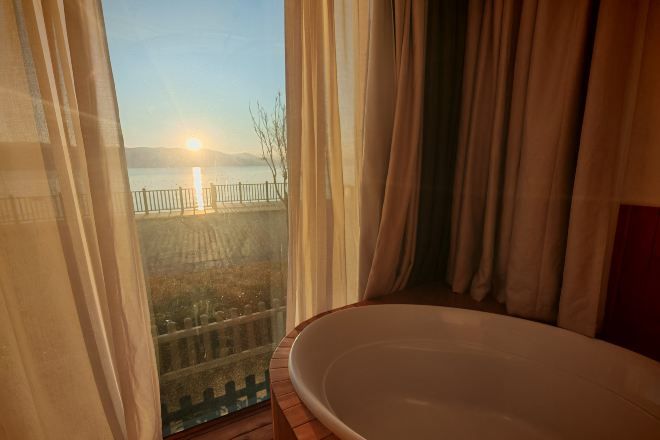 Une pièce dotée d’une grande fenêtre donnant sur une étendue d’eau et sur une côte lointaine.