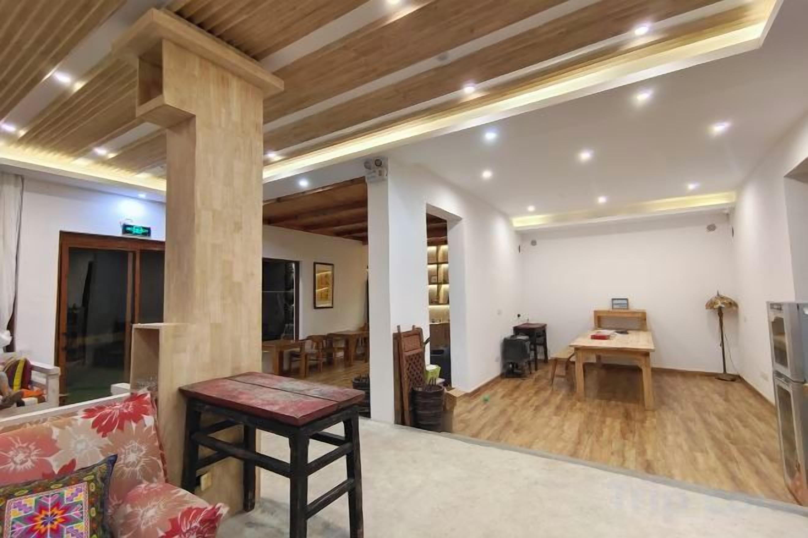 A hotel lobby with a wooden ceiling, a reception desk, a dining area, and a large pillar.