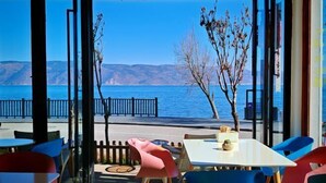 A restaurant with a view of the sea, featuring colorful chairs and a table with a vase. - HillSea Green Holiday Inn , Dali (Dali City)