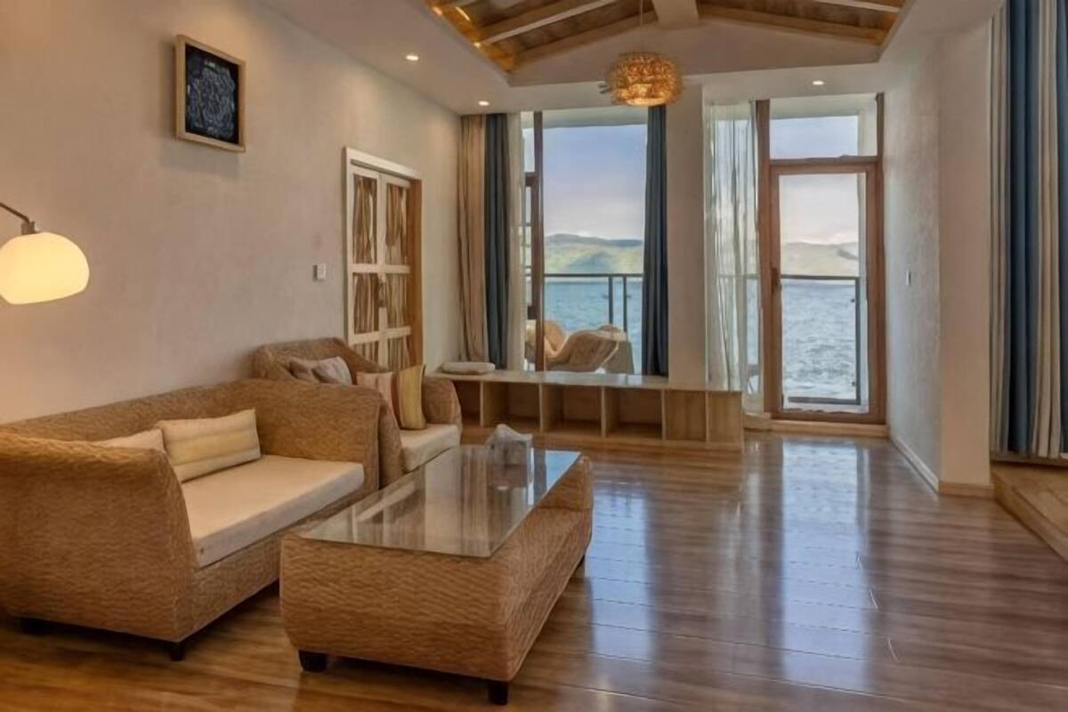 Un vaste espace de vie comprenant un canapé, une table basse et une vue sur la mer grâce à de grandes fenêtres.