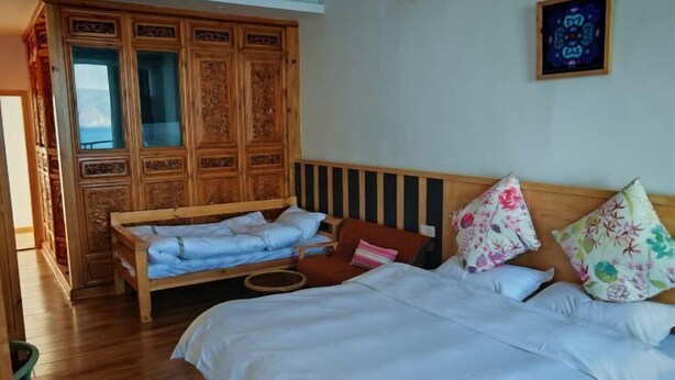 A room with a bed, a wooden wardrobe, and a wall-mounted artwork. - HillSea Green Holiday Inn , Dali (Dali City)
