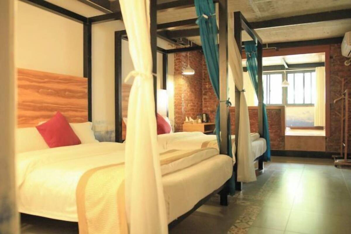 A hotel room with a bed, a window, and a brick wall.
