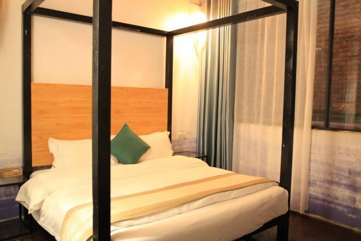 A four-poster bed with a wooden headboard, a green pillow, and a white bedspread.
