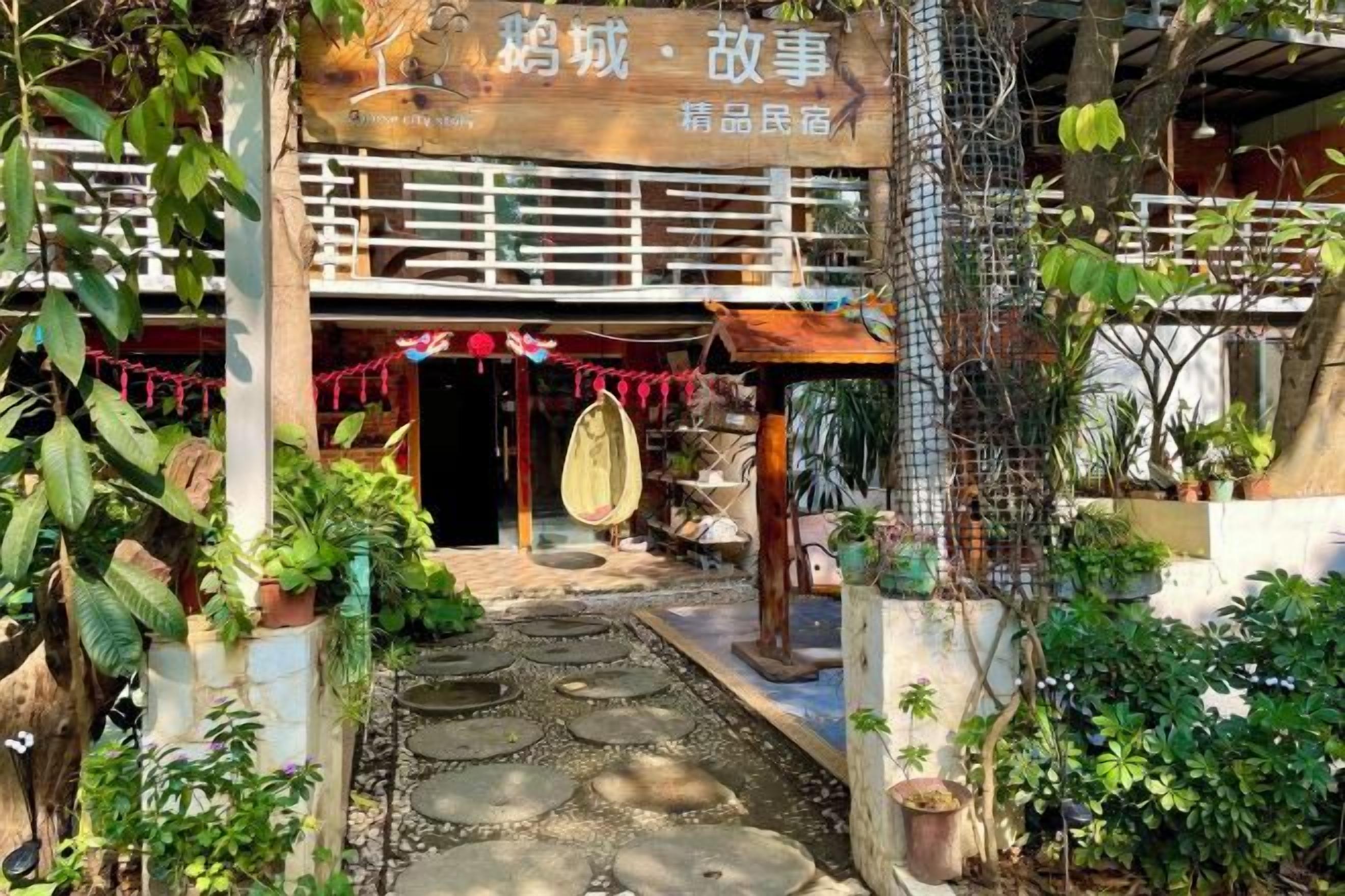 A traditional building with a wooden facade, a tiled entrance, and a garden area with potted plants.