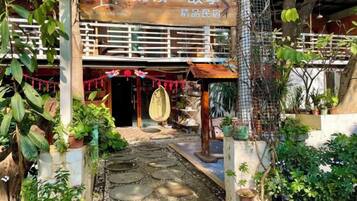 A traditional building with a wooden facade, a tiled entrance, and a garden area with potted plants.