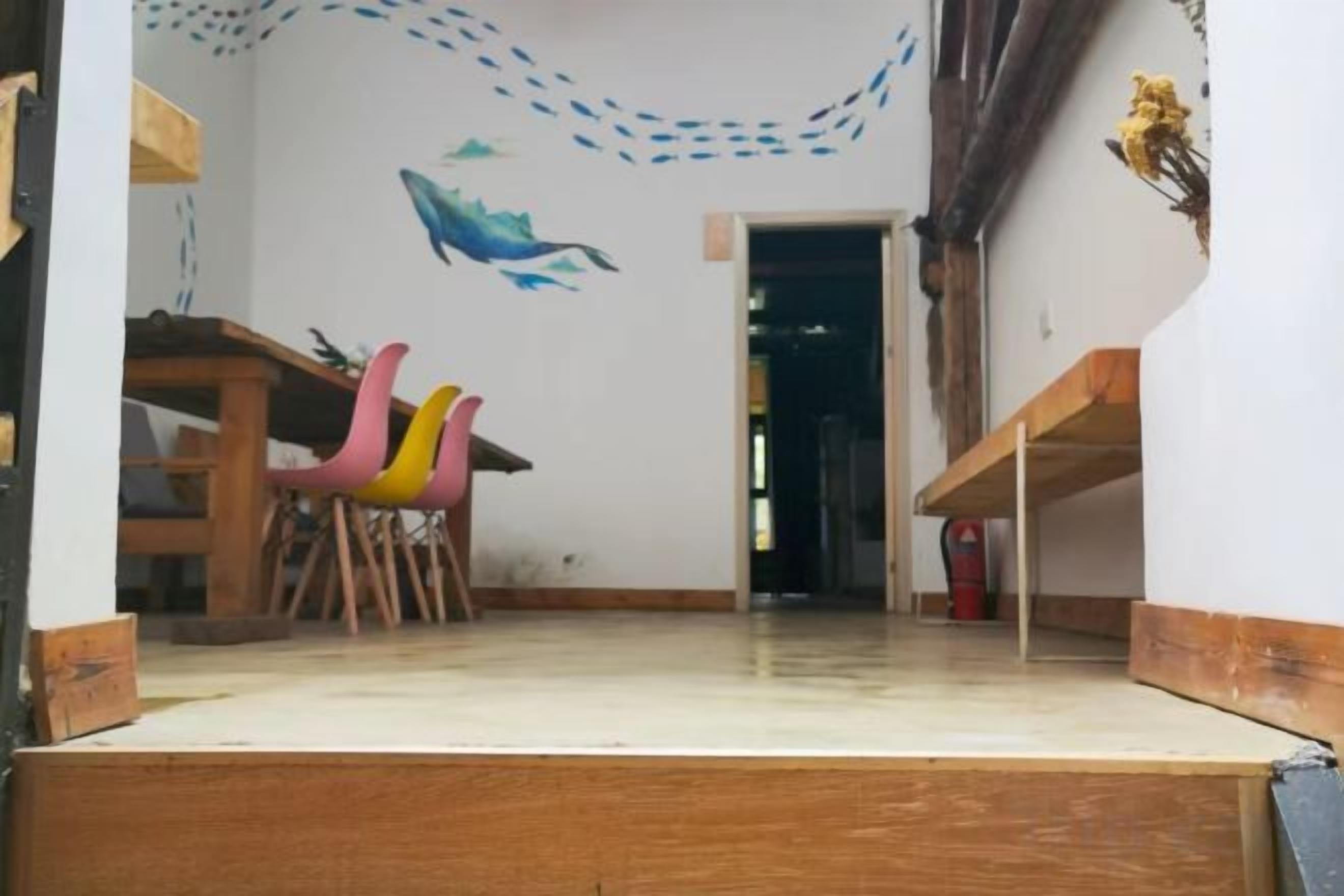 Une pièce avec un bureau en bois, une chaise et un élément de décoration murale aux couleurs vives.