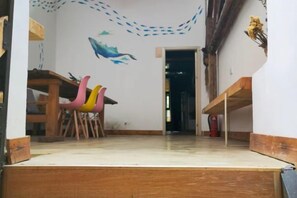 A room with a wooden desk, a chair, and a colorful wall decoration. - Goose city story (Baise)