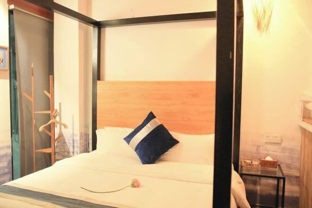 A bed with a wooden headboard, a single pillow, and a small bedside table with a box.