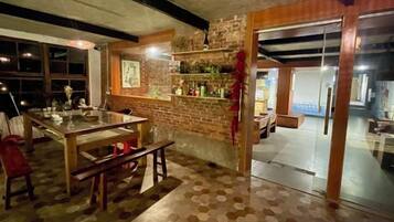 A room with a dining table, benches, a brick wall, and a glass door leading to another area.