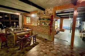 Een kamer met een eettafel, bankjes, een bakstenen muur en een glazen deur die leidt naar een ander gedeelte.