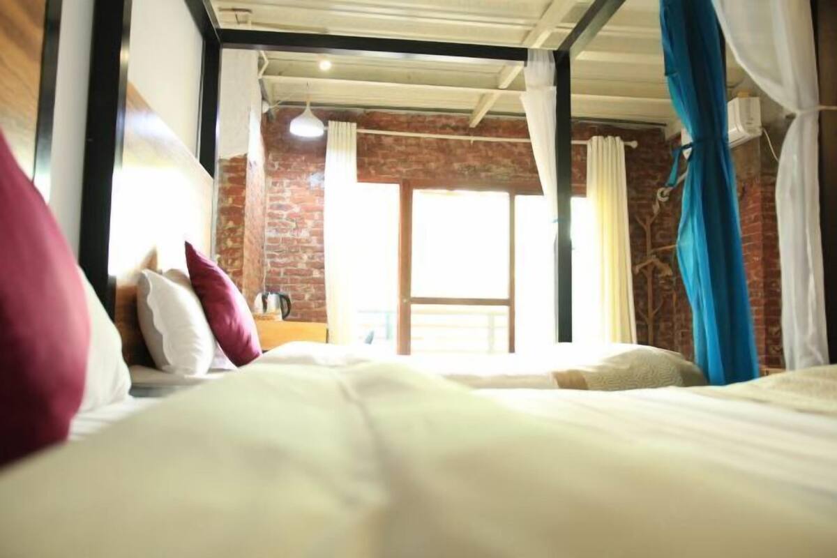 A room with a bed, a window, and a brick wall.