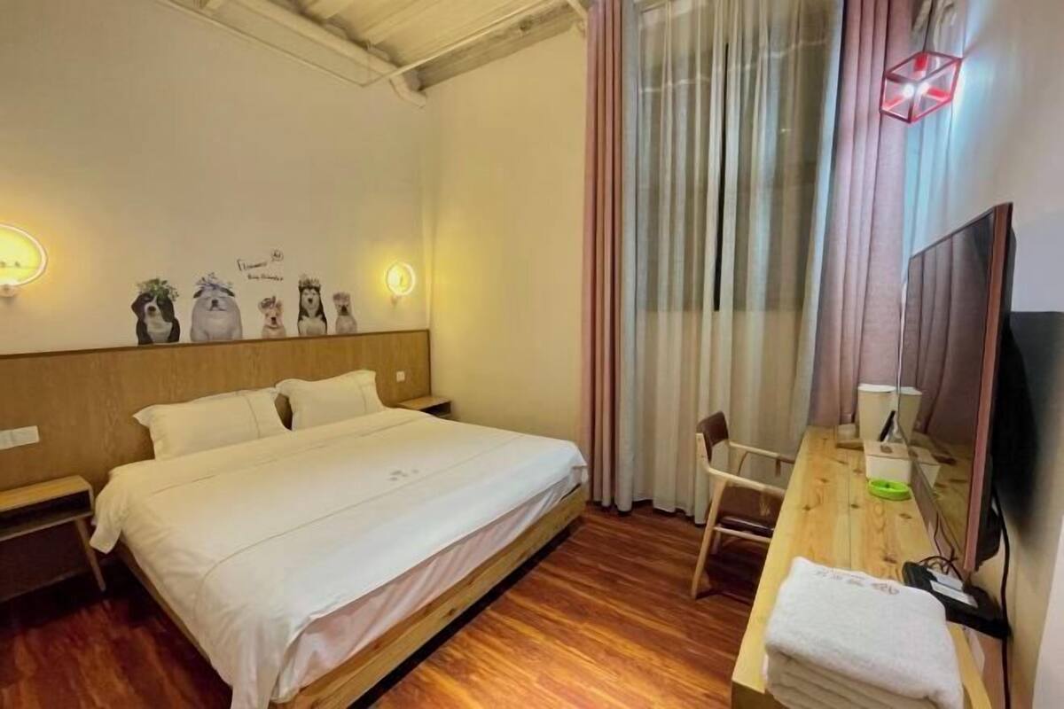 A bedroom with a bed, bedside tables, a desk with a chair, a TV, and a window with curtains.