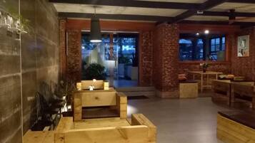 A spacious lobby with a wooden reception desk, seating area, and a view of the outdoors.