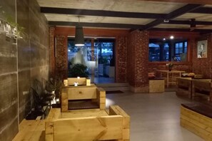 A spacious lobby with a wooden reception desk, seating area, and a view of the outdoors. - Goose city story (Baise)