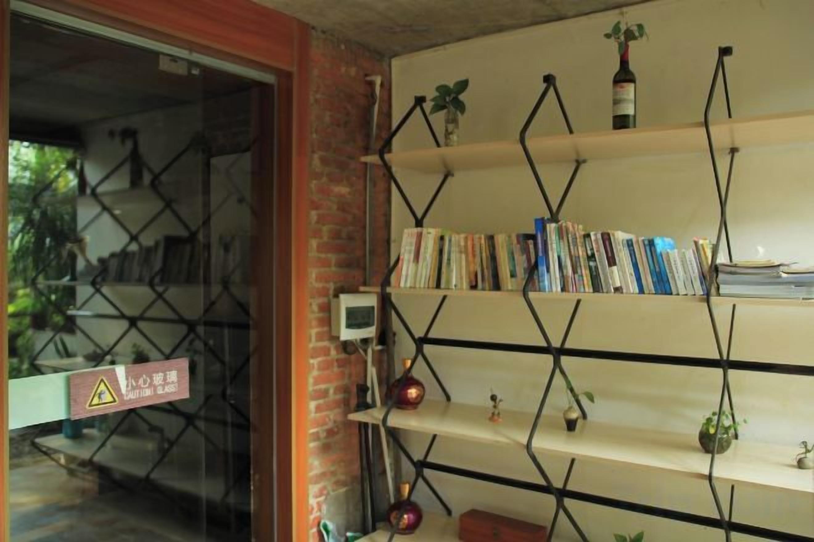 Une pièce avec un mur en briques, une bibliothèque remplie de livres et une petite plante posée sur l’étagère du haut.