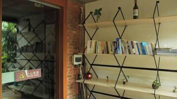 A room with a brick wall, a bookshelf with books, and a small plant on the top shelf.