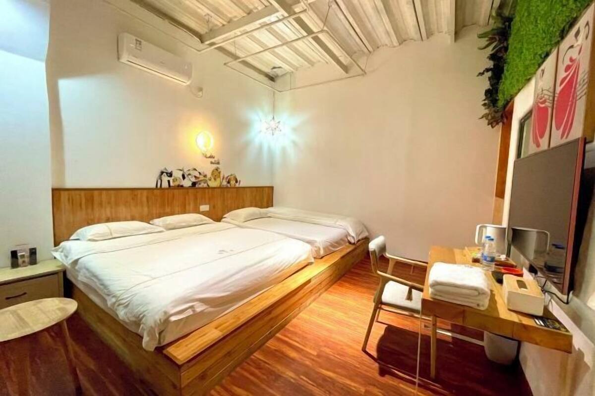 A room with a wooden bed, a desk with a chair, a TV, and a wall-mounted mirror.