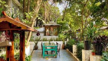 A garden with a table and chairs, a gazebo, and various plants.